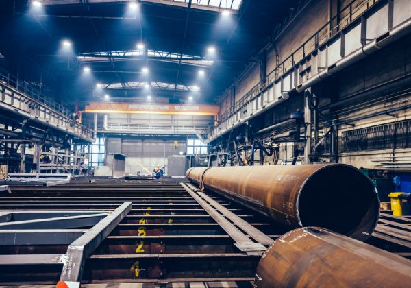 Pipe in the manufacturing process in the factory with employees in the distant