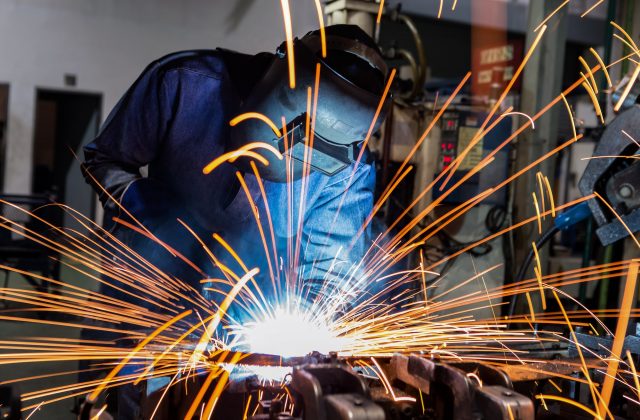 Employee cutting steel with sparks flying wearing safety gear